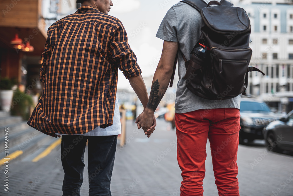 Serious man holding arm of another guy while walking on street with him.  They turning back to camera Stock Photo | Adobe Stock