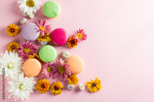 Still life and food photo of cake macarons in a gift box with flowers  a cup of tea on light background. Sweets and desserts concept of macaroons.