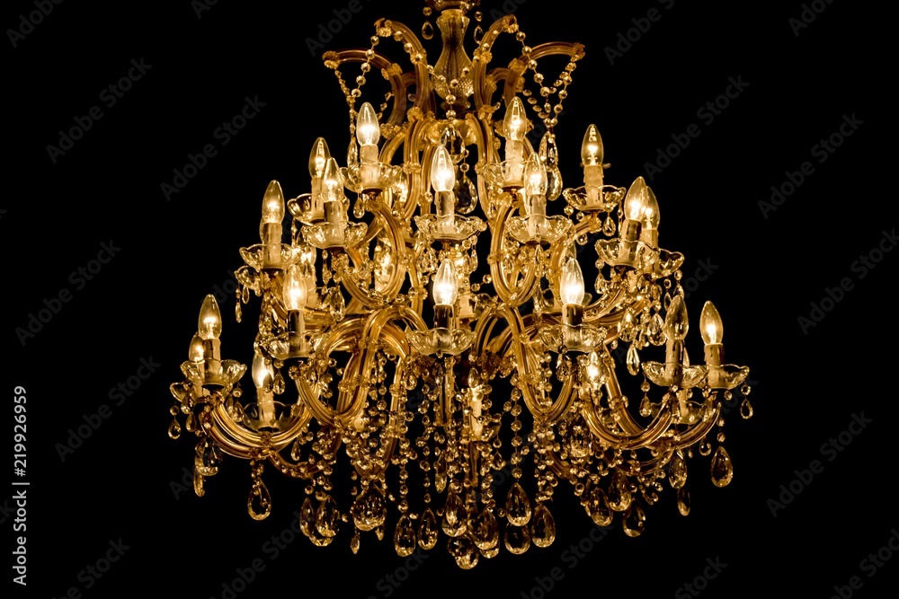 Luxury interior chandelier has light candles and dark background. Noble  candelabra hanging on ceiling with lots of little gems. Premium decoration  for palace gala, villa business meeting or wedding Stock Photo