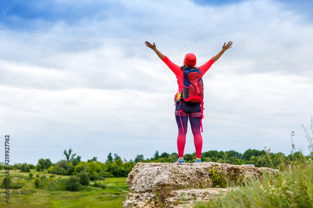 Image from back of female tourist with arms raised on hill Image from back of female tourist with arms raised on hill