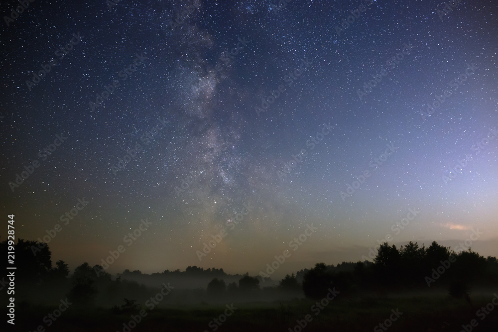 Starry night sky in the northern hemisphere. View of the Milky Way over a meadow with fog. Long exposure. Starry night sky in the northern hemisphere. View of the Milky Way over a meadow with fog. Long exposure.