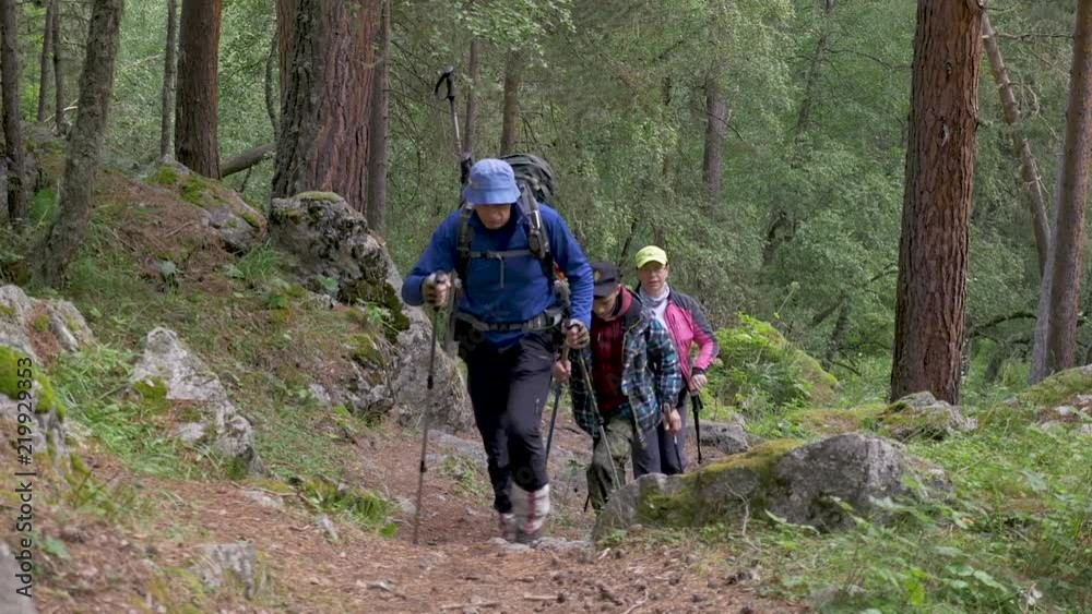 Family: father, son and mother walking along the mountain path. They travel in the mountains of the Caucasus with backpacks behind their shoulders. Family: father, son and mother walking along the mountain path. They travel in the mountains of the Caucasus with backpacks behind their shoulders.