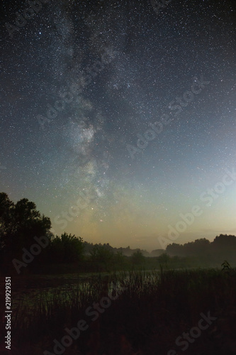 Starry night sky in the northern hemisphere. View of the Milky Way over a lake with a mist. Long exposure.