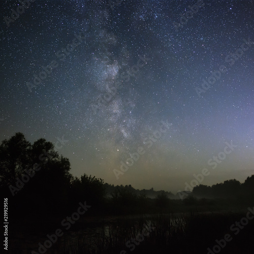 Starry night sky in the northern hemisphere. View of the Milky Way over a lake with a mist. Long exposure. © olgapkurguzova
