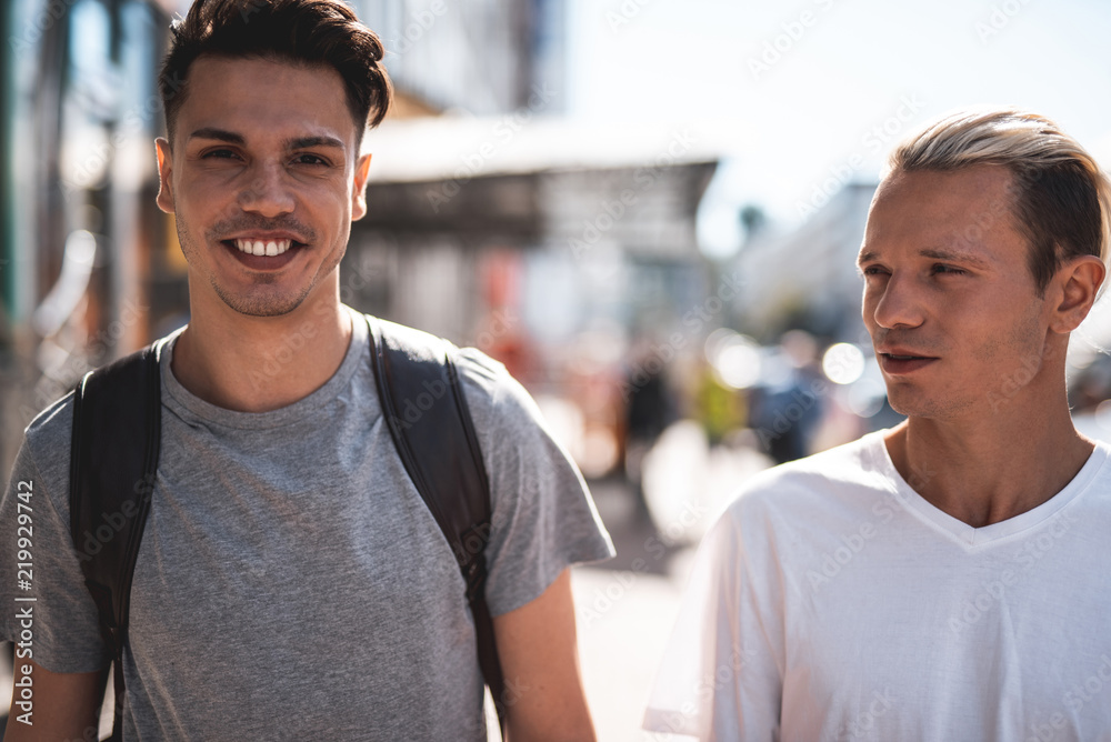 Obraz premium Portrait of beaming male telling with orderly man while going at street