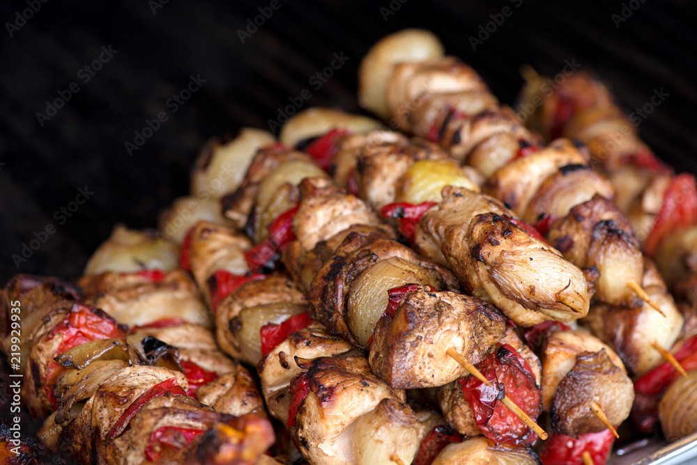 Close up of traditionally grilled pork and beef meat on a wooden stick. Eastern European traditional shish kebab with grilled vegetables.