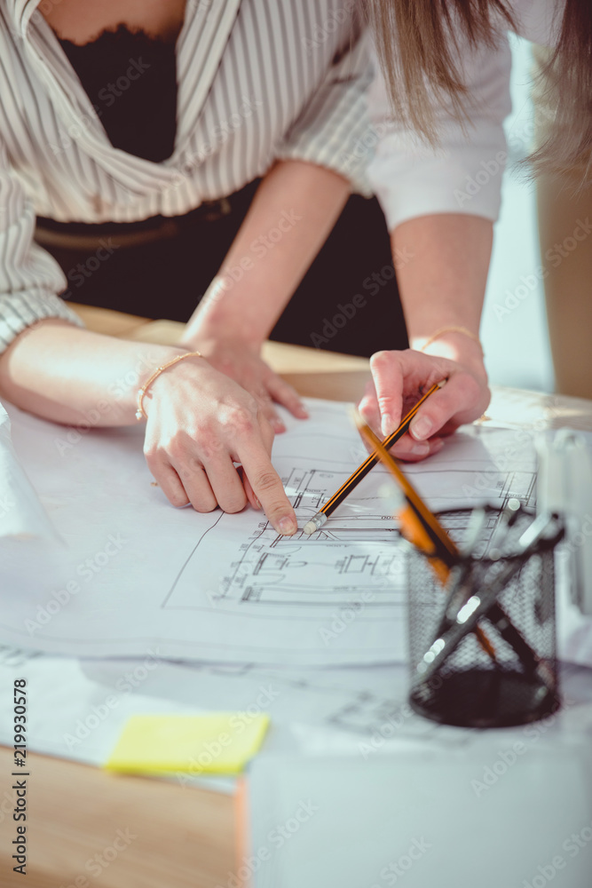 cropped shot of young designers pointing with finger on blueprints