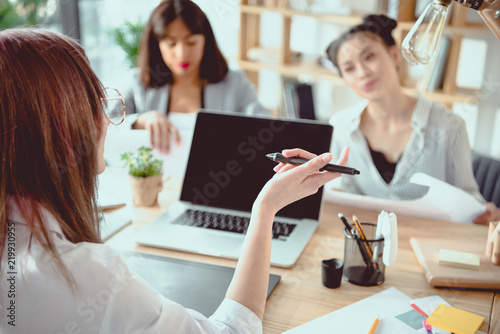 young multiethnic architects with digital devices and blueprints working at office