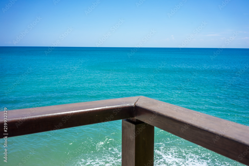 wood hand rail and ocean horizon with turquoise water