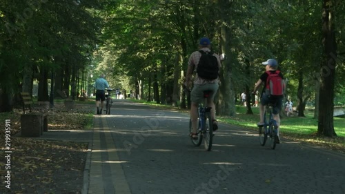 Wallpaper Mural People ride a bicycle in a park amongst green trees in a summer sunny day Torontodigital.ca
