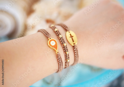 woman hand wearing stylish brown bracelets with evil eye and cross - macrame bracelets - greek jewelry
