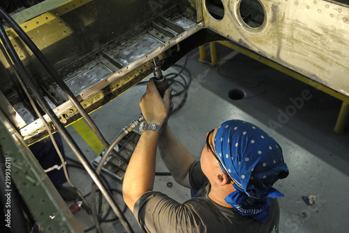 Fitter works with a screwdriver preparing the body plane for further riveting