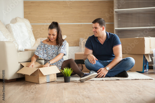 Young couple moving in a new home.Man and woman unboxing fragile stuff. photo