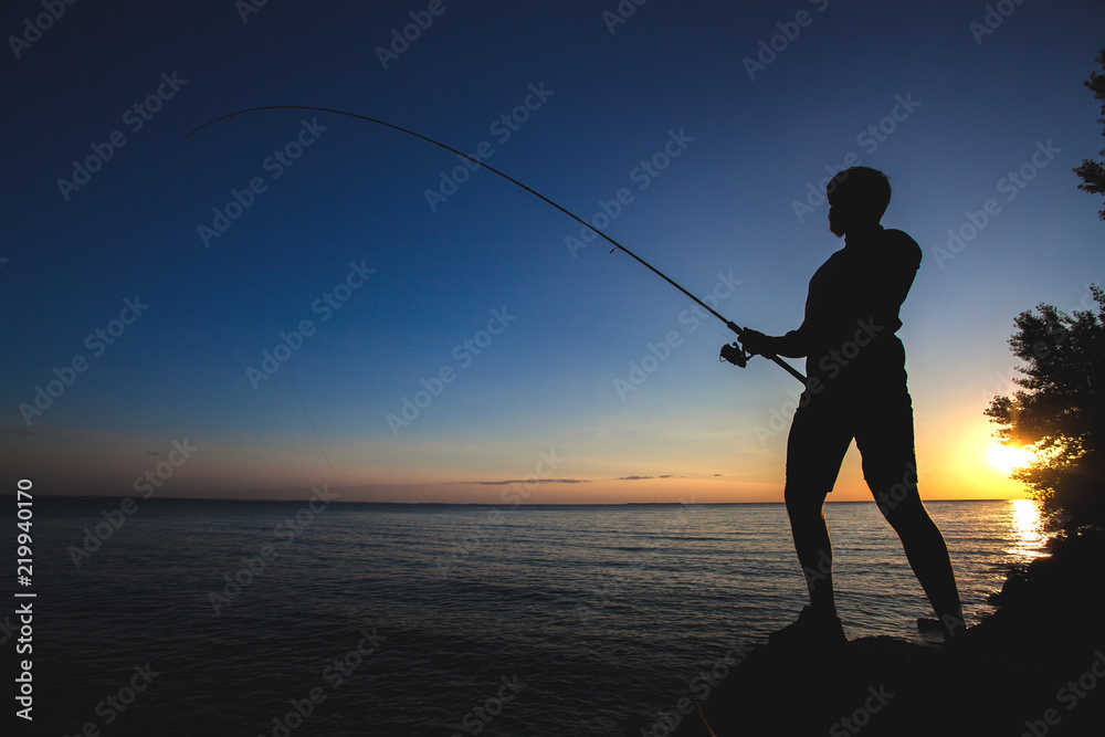 silhouette of a fisherman on the background of the setting sun