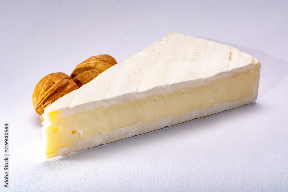 Piece of french soft-ripened white mold cow milk cheese brie produced in Seine-et-Marne region, France, isolated on white