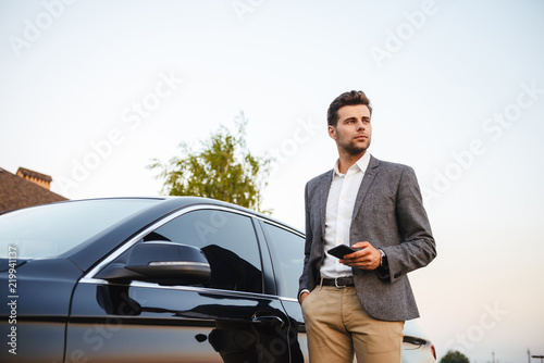 Confident young businessman in suit standing at his car © Drobot Dean
