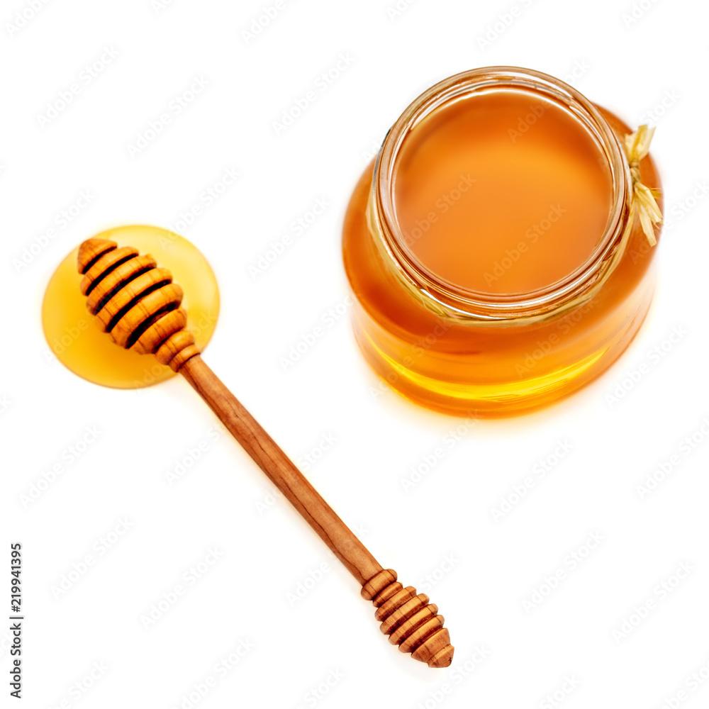Wooden dipper with dripping honey and glass jar isolated on white background, macro Wooden dipper with dripping honey and glass jar isolated on white background, macro
