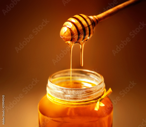 Honey in jar with honey dipper on rustic wooden table background. Copy space. photo