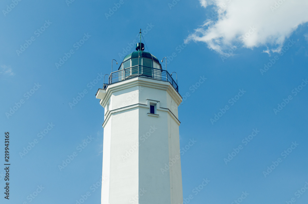 White lighthouse against the blue sky on a sunny day