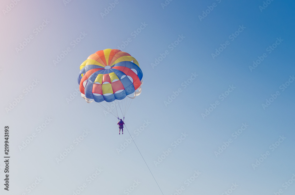 A man flying on a parachute over the sea with a boat A man flying on a parachute over the sea with a boat