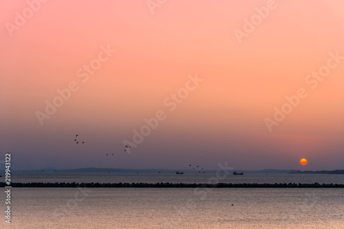 Sunset over the Black Sea, Krasnodar Krai, Russia. Silhouettes of barges and flying birds on a sunset background.