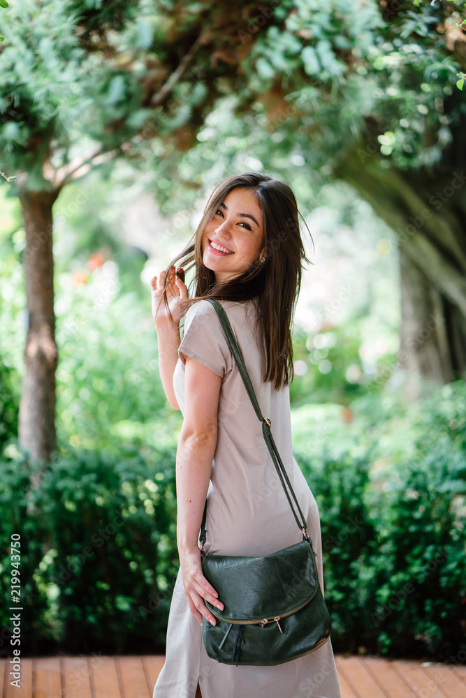Portrait of a young, attractive and elegant Japanese Asian tourist posing in a park during the day. She is cute and smiling happily for her photograph. 