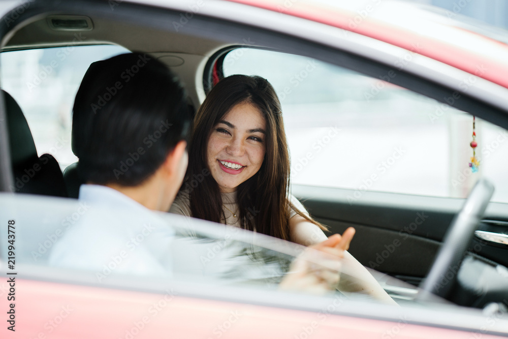 A young attractive Japanese couple are going on a trip in a red car. Both of them look happy and excited to reach their destination. A young attractive Japanese couple are going on a trip in a red car. Both of them look happy and excited to reach their destination.
