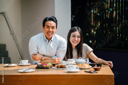 A young and attractive Asian couple take photographs of their tea meal before they dig in.