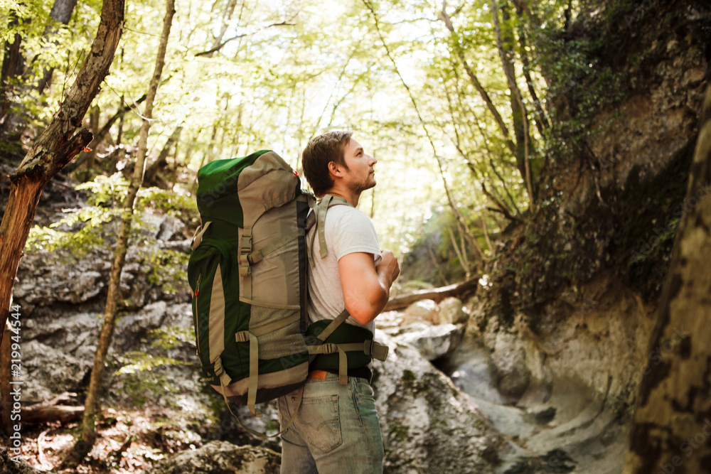 A man with a backpack and a karemate goes on a trek through the rocky gorge. Space for text. A man with a backpack and a karemate goes on a trek through the rocky gorge. Space for text.