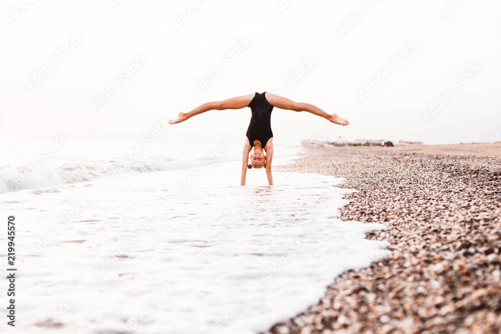 A gymnast in a beautiful pose against the background of the ocean.