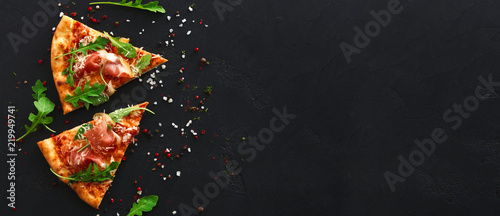 Tela Slices of pizza with spices on black background