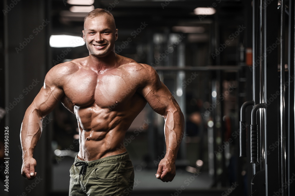 Handsome strong bodybuilder athletic men pumping up muscles with dumbbells