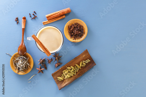 stick of cinnamon lies on a glass glass with Masala tea on a background of spices of ingredients cinnamon, cardamom, ginger, cloves, tubby, sweet pepper. Top view. Copy space
