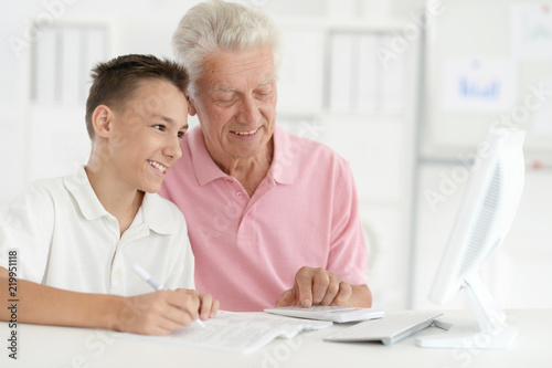 Portrait of a boy and grandfather with computer at home
