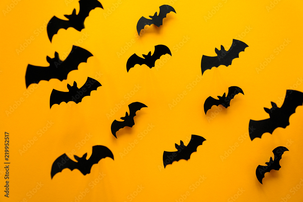 Naklejka premium Black paper bats flying on yellow background. Halloween concept. Paper cut style. Top view