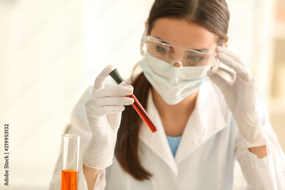 Female scientist holding test tube with color sample in laboratory