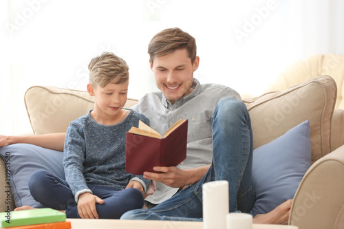 Father and his son reading book together at home