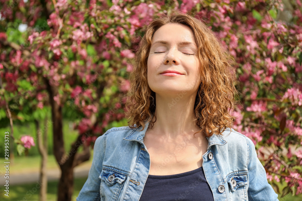 Portrait of beautiful woman near blooming tree in park Portrait of beautiful woman near blooming tree in park