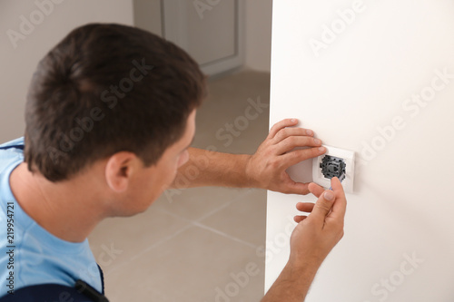 Electrician repairing wall ...