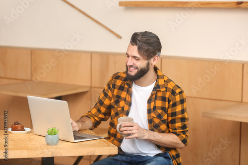 Young man using laptop whil...