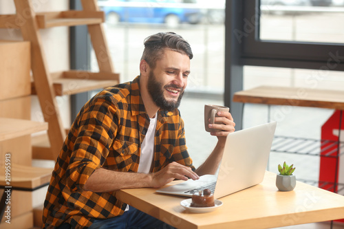 Young man using laptop whil...
