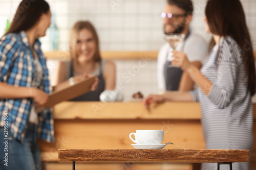 Cup of delicious hot coffee on wooden table in bar
