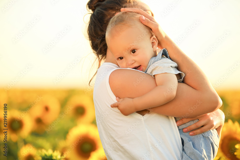 Beautiful woman with her little son in sunflower field on sunny day Beautiful woman with her little son in sunflower field on sunny day