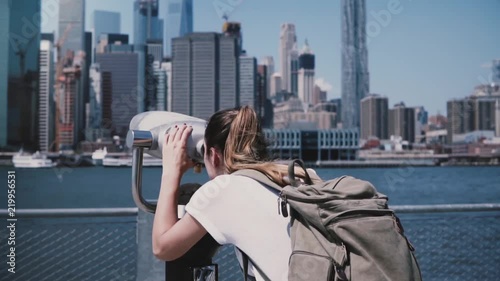 Back view young tourist girl looks through coin-operated binocular at city panorama of Manhattan, New York slow motion.
