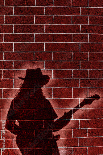 Shadow of musician whit guitar on brick wall 
