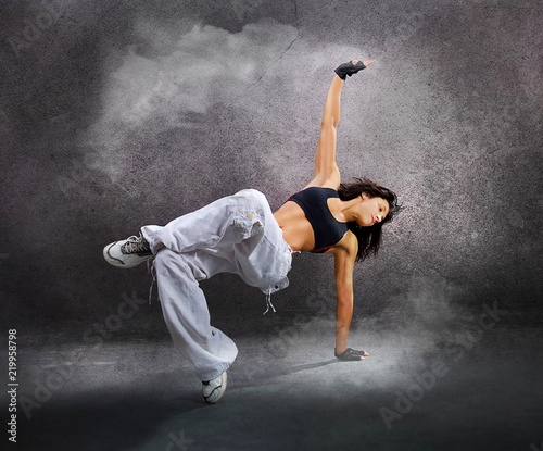 Young beautiful athletic woman jumping dancing modern style dance hip-hop  on studio on wall background with smoke Stock Photo | Adobe Stock