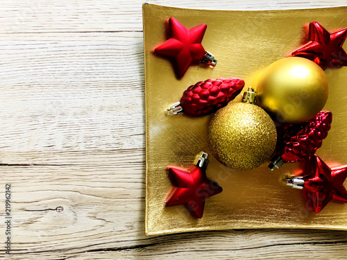 christmas decorations in red and gold over gold tray on wooden table photo