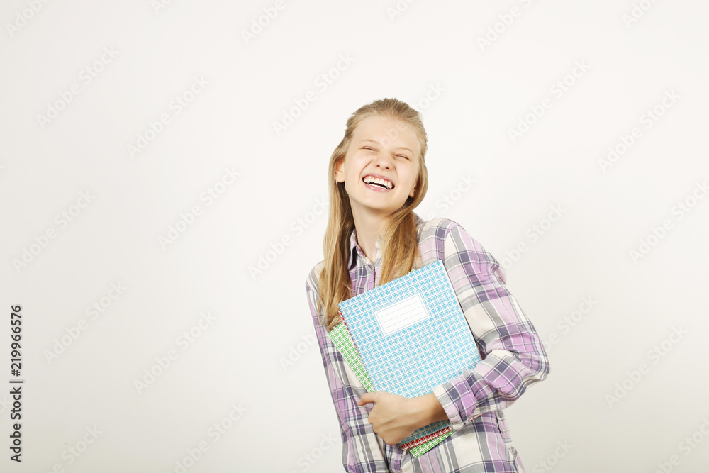 Beautiful blonde teenage girl with charming smile in schoolgirl uniform wearing pleated skirt, white shirt, holding notebooks. Back to school sale concept. Background, copy space, close up, isolated. Beautiful blonde teenage girl with charming smile in schoolgirl uniform wearing pleated skirt, white shirt, holding notebooks. Back to school sale concept. Background, copy space, close up, isolated.