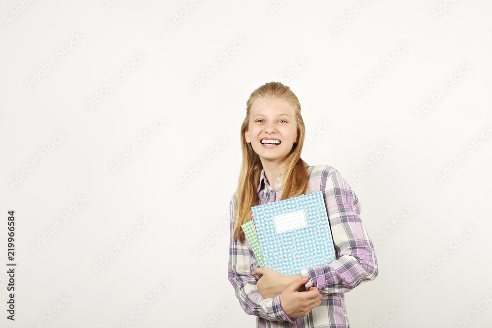 Beautiful blonde teenage girl with charming smile in schoolgirl uniform wearing pleated skirt, white shirt, holding notebooks. Back to school sale concept. Background, copy space, close up, isolated. Beautiful blonde teenage girl with charming smile in schoolgirl uniform wearing pleated skirt, white shirt, holding notebooks. Back to school sale concept. Background, copy space, close up, isolated.