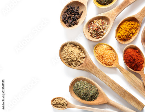 Wooden spoons with different spices on white background